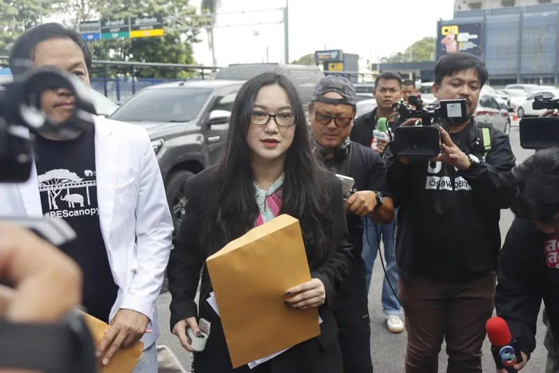 ออยศรีถือซองเอกสารขณะอยู่กับกลุ่มผู้สื่อข่าวในภาพแนบรายงานการยื่นกองปราบ